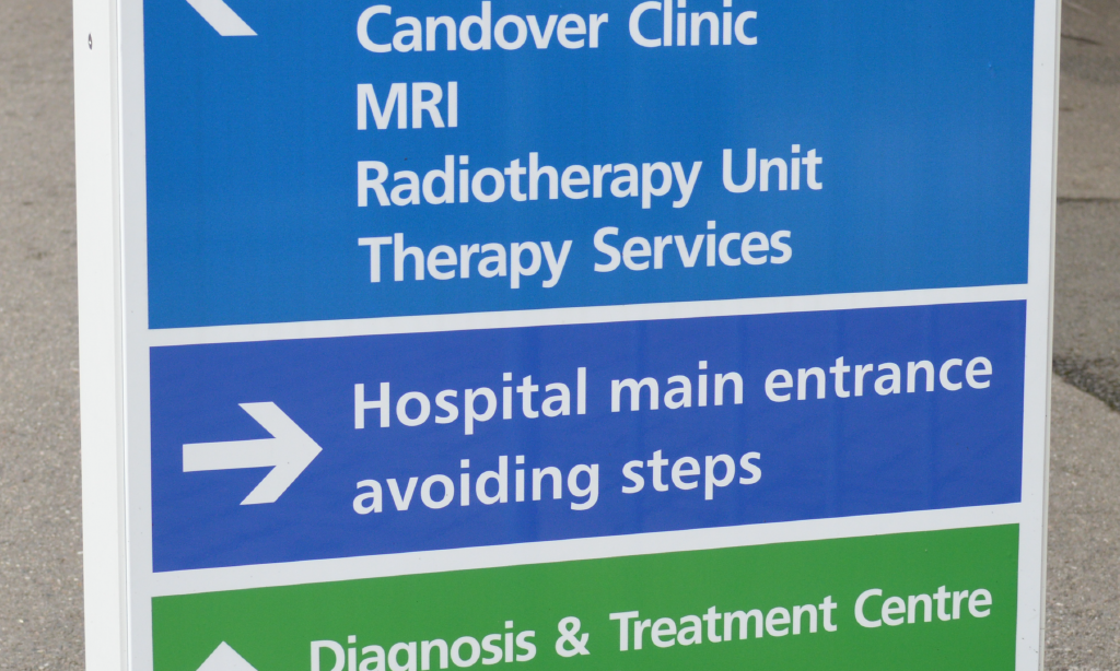 A hospital entrance sign directing patients to various departments