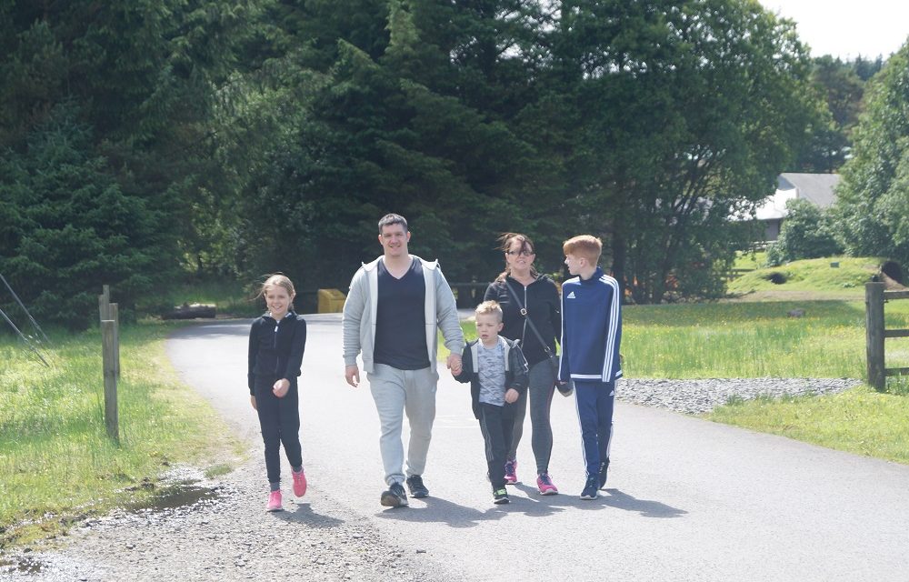 Family of five, enjoying a healthy stroll, which helps to stay well particularly to manage a brain tumour, one of the many benefits of exercise.