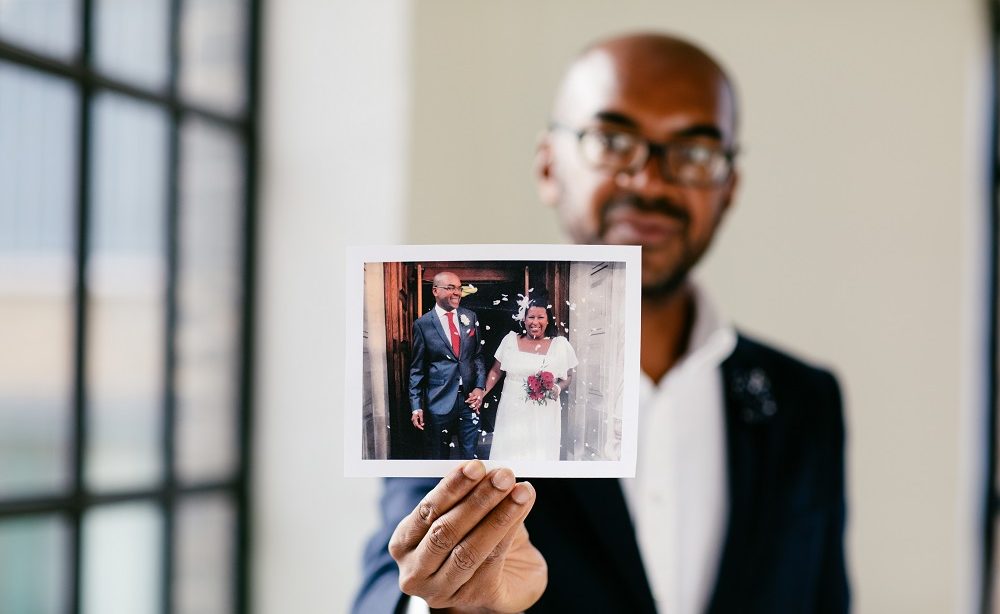 Man holding wedding day photo, sharing his story to raise awareness about brain tumours.