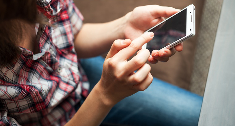 A lady holding a mobile phone accessing various medical resources, identifying those specific to brain tumour diagnosis and treatment