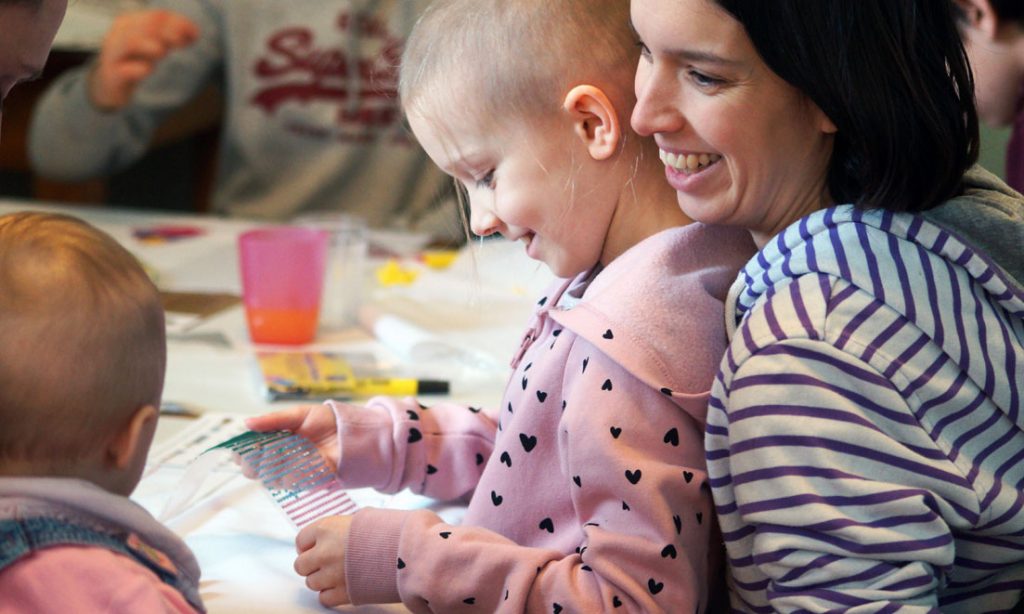 a mother sits with her child in her lap, the child is coping with the side effects of child brain tumour treatments