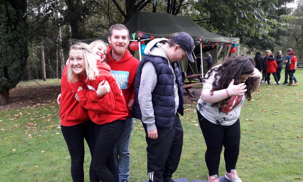 Five young adults mess around in front of the camera at one of The Brain Tumour Charity's Young Adult Meet Ups. They're all smiling and many are dressed in The Brain Tumour Charity branded hoodies.