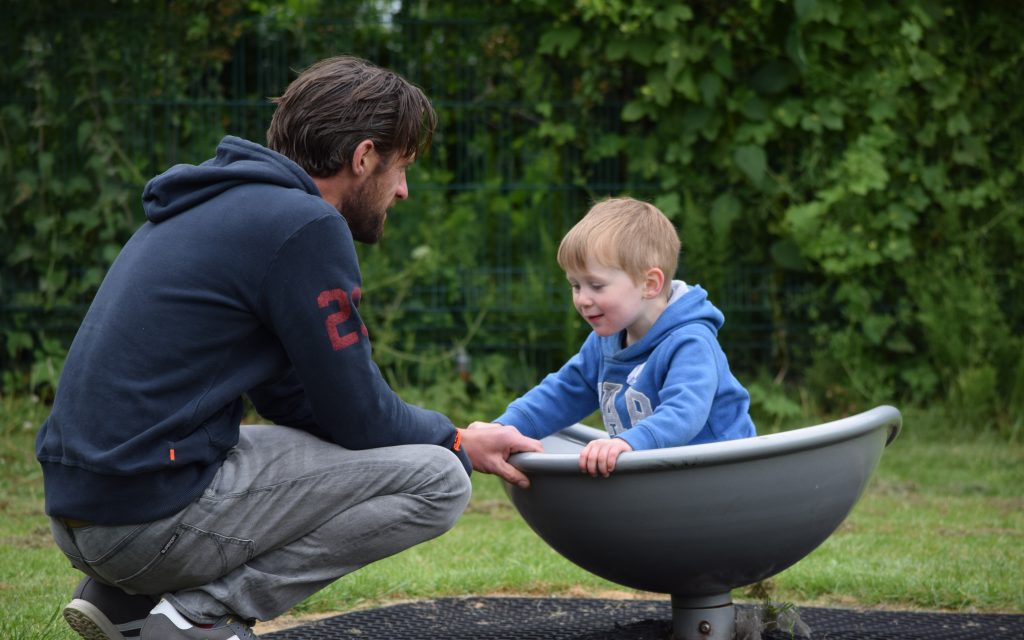 A father plays with his son in a playground