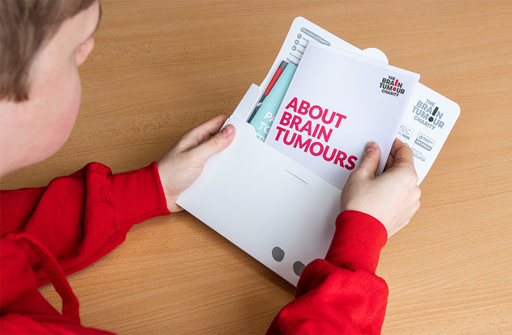 A young man opening a free information pack on brain tumours 