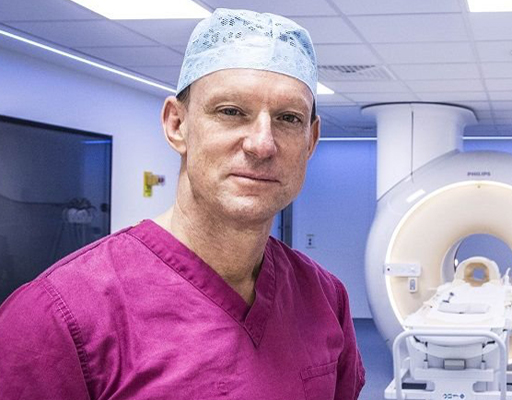 A surgeon stands in front of an MRI machine 