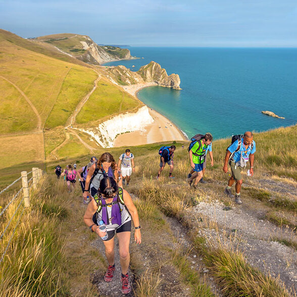 People walking on the side of a cliff with the ocean in the background during the Jurassic Coast Ultra Challenge