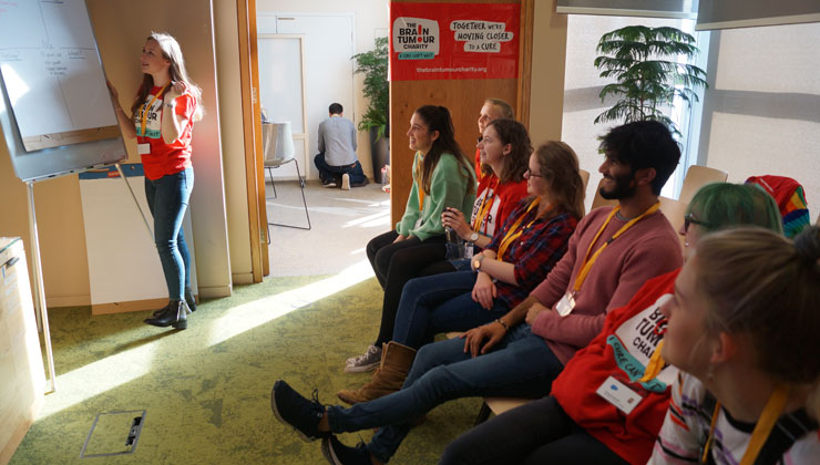 A young woman presenting to a group at The Brain Tumour Charity. You can use your experience to volunteer and help others affected by brain tumours.