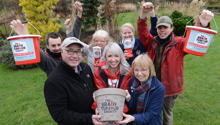 A group of people hold donation buckets for The Brain Tumour Charity. You can volunteer in your community this way.