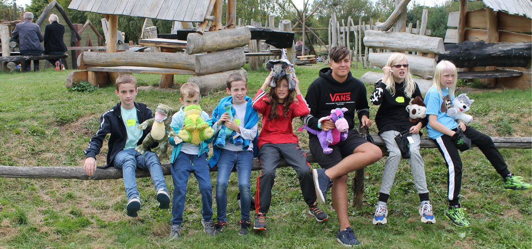 A group of children affected by brain tumours sit together on a bench in front of an adventure playground at one of The Brain Tumour Charity's Family Days.