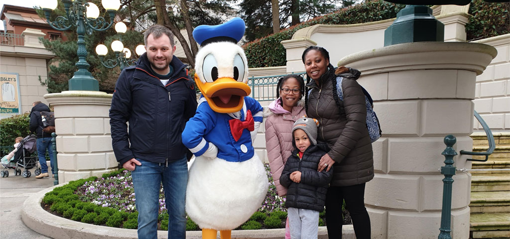 Karla, her partner and two children pose for a photograph with Donald Duck at Disneyland.