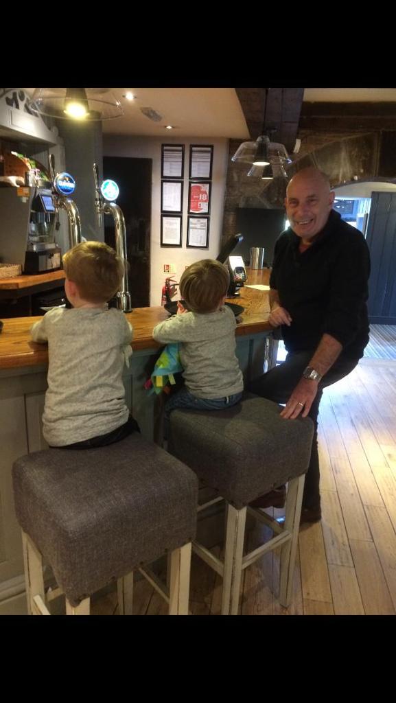 A man and two children sat on bar stools in a pub.