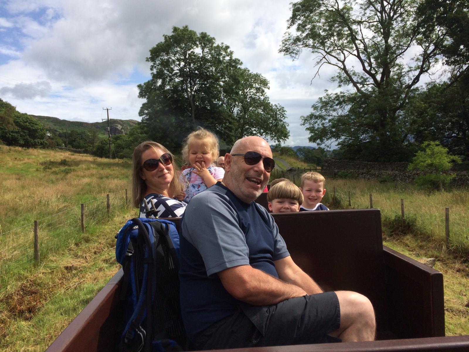 A man and a woman with three children, they are sitting on an open train carriage.