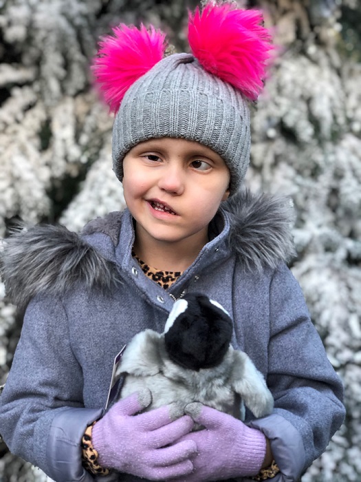 Ella, a child with a brain tumour, holding a cuddly toy on a snowy day