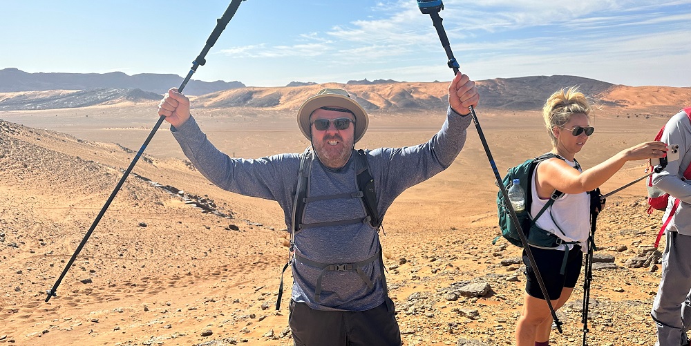 Hal Cruttenden cheering while holding walking poles in the Sahara