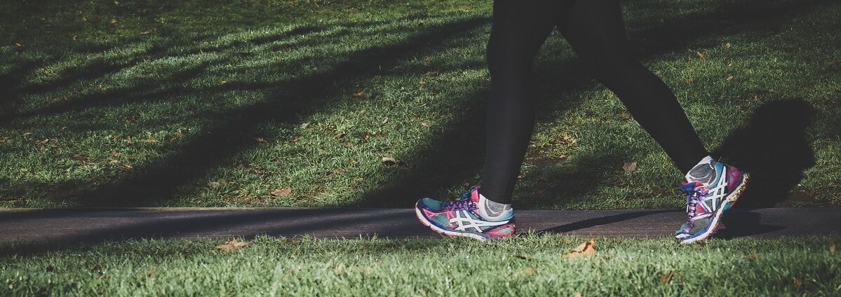 woman's legs in park walking for wellness