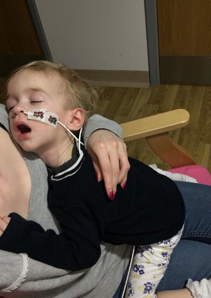 young child with a brain tumour resting on a parent