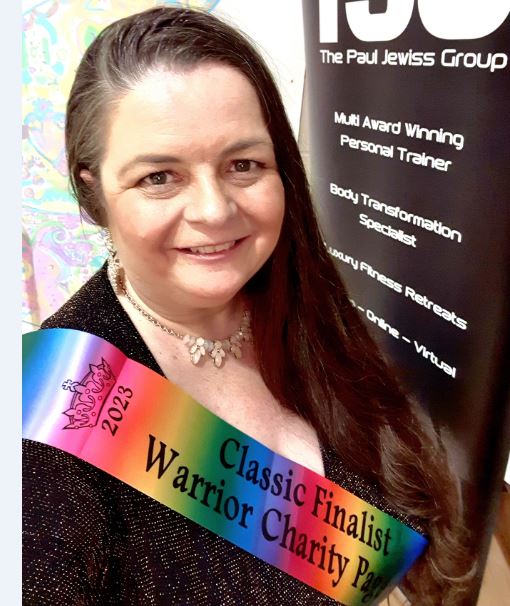 Karen Bucknall wearing a rainbow colour sash that says "Classical Finalist Warrior Charity Pageant".