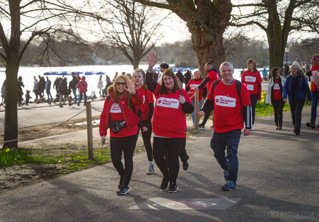 A crowd of people wave while enroute at The Twilight Walk 2023