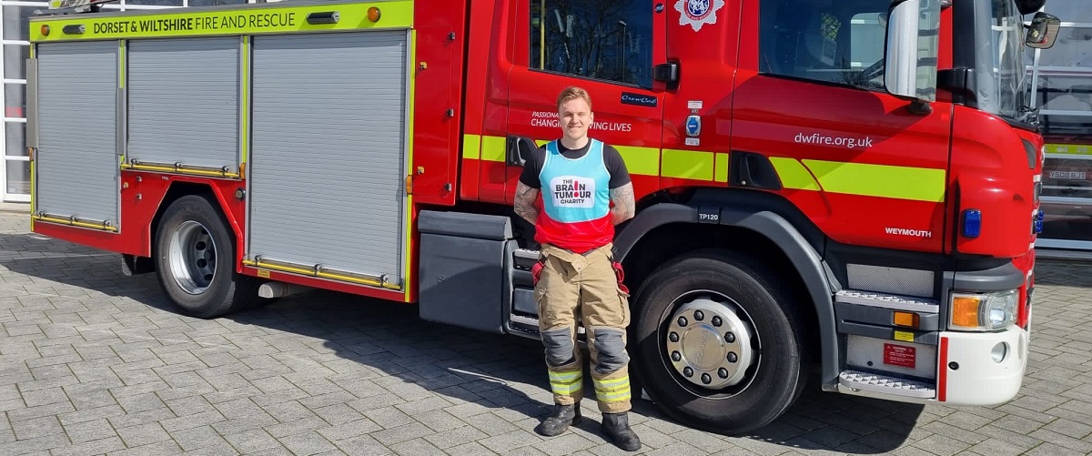 Man standing in front of a fire engine wearing a The Brain Tumour Charity running vest