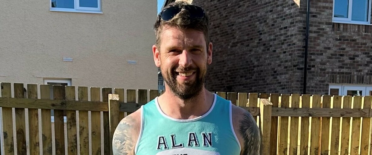 Alan smiling while standing in a garden wearing a The Brain Tumour Charity running vest