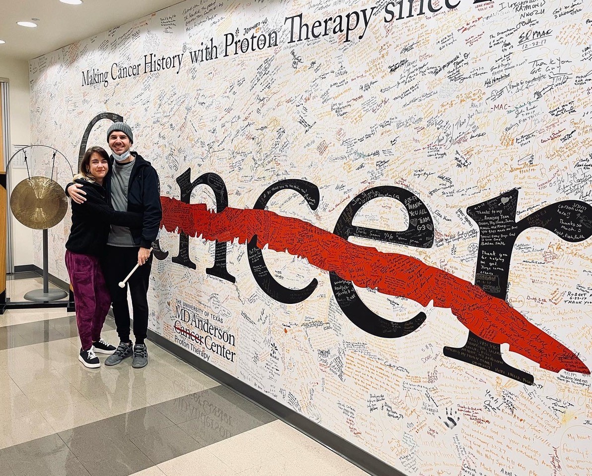 Josh Martin and partner standing in front of a wall at MD Anderson Cancer Center in Texas