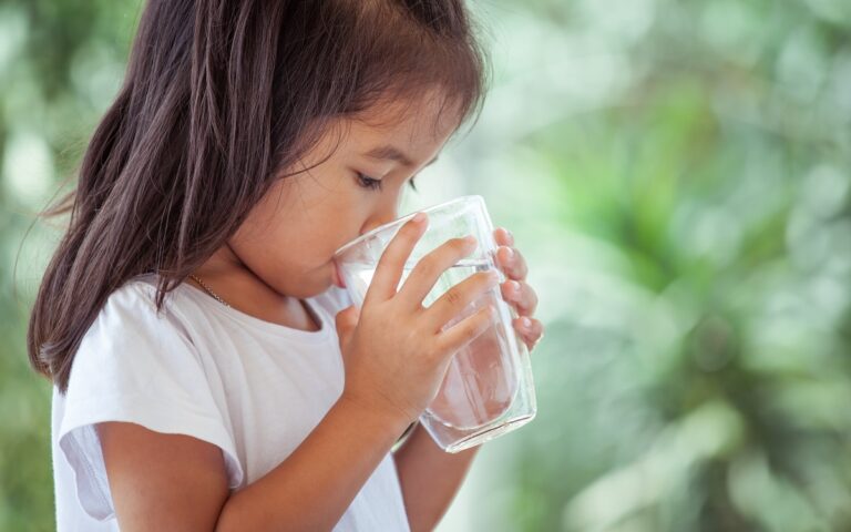 child drinking a glass of water while experiencing excessive thirst