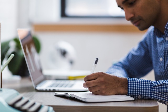 a man at a desk with a laptop and notepad