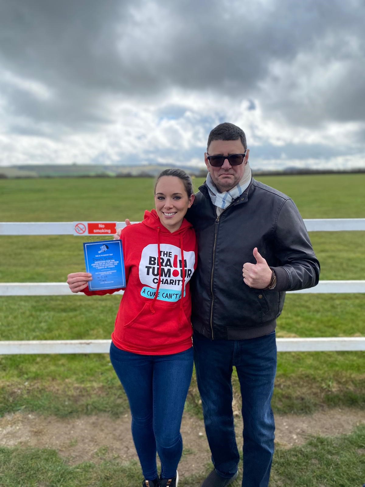 Danni stands in her The Brain Tumour Charity hoodie with her dad who she is completing her extreme fundraising challenge for