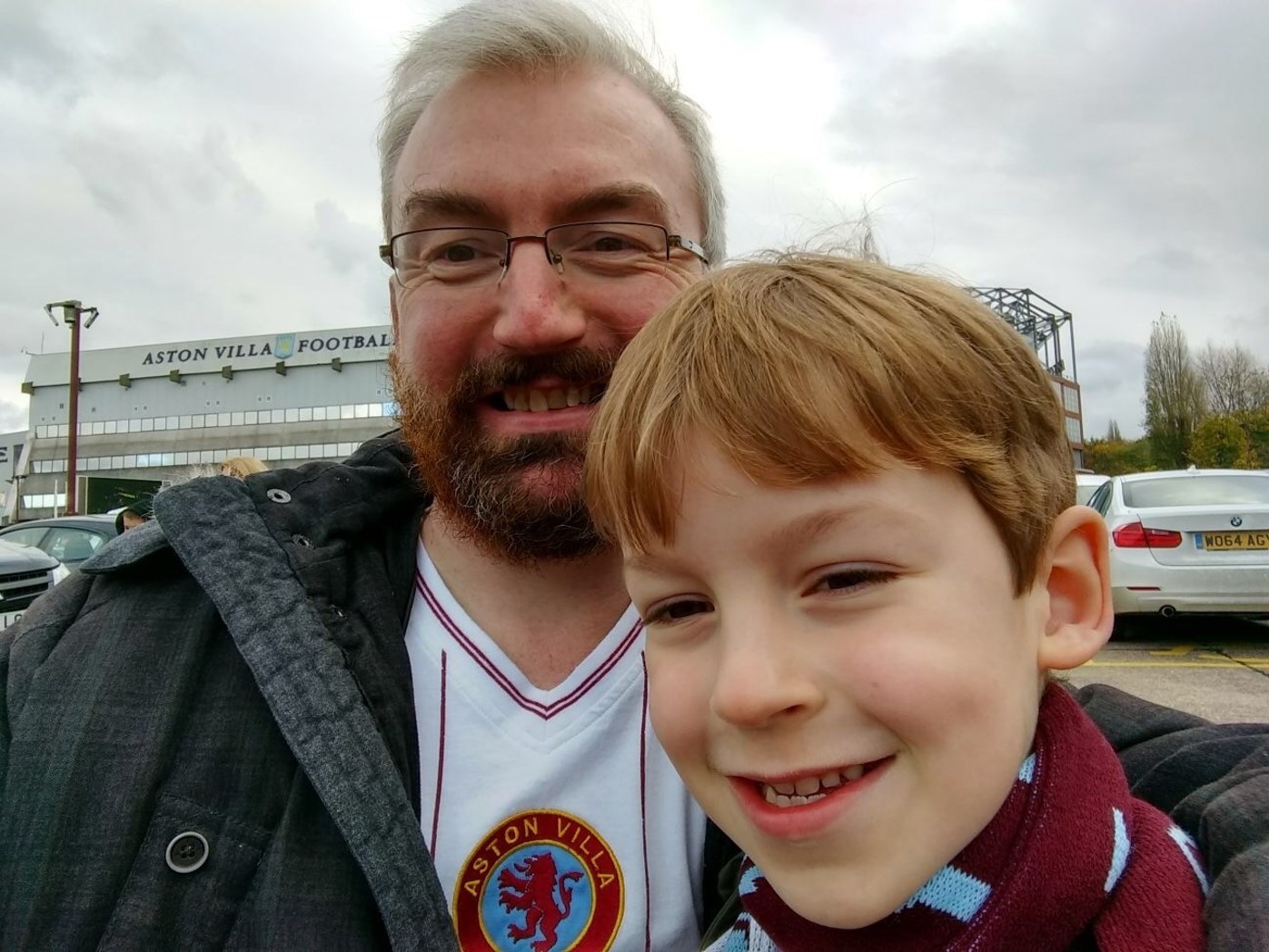 Peter and his son wearing Aston Villa football shirts, in front of the Aston Villa football stadium.