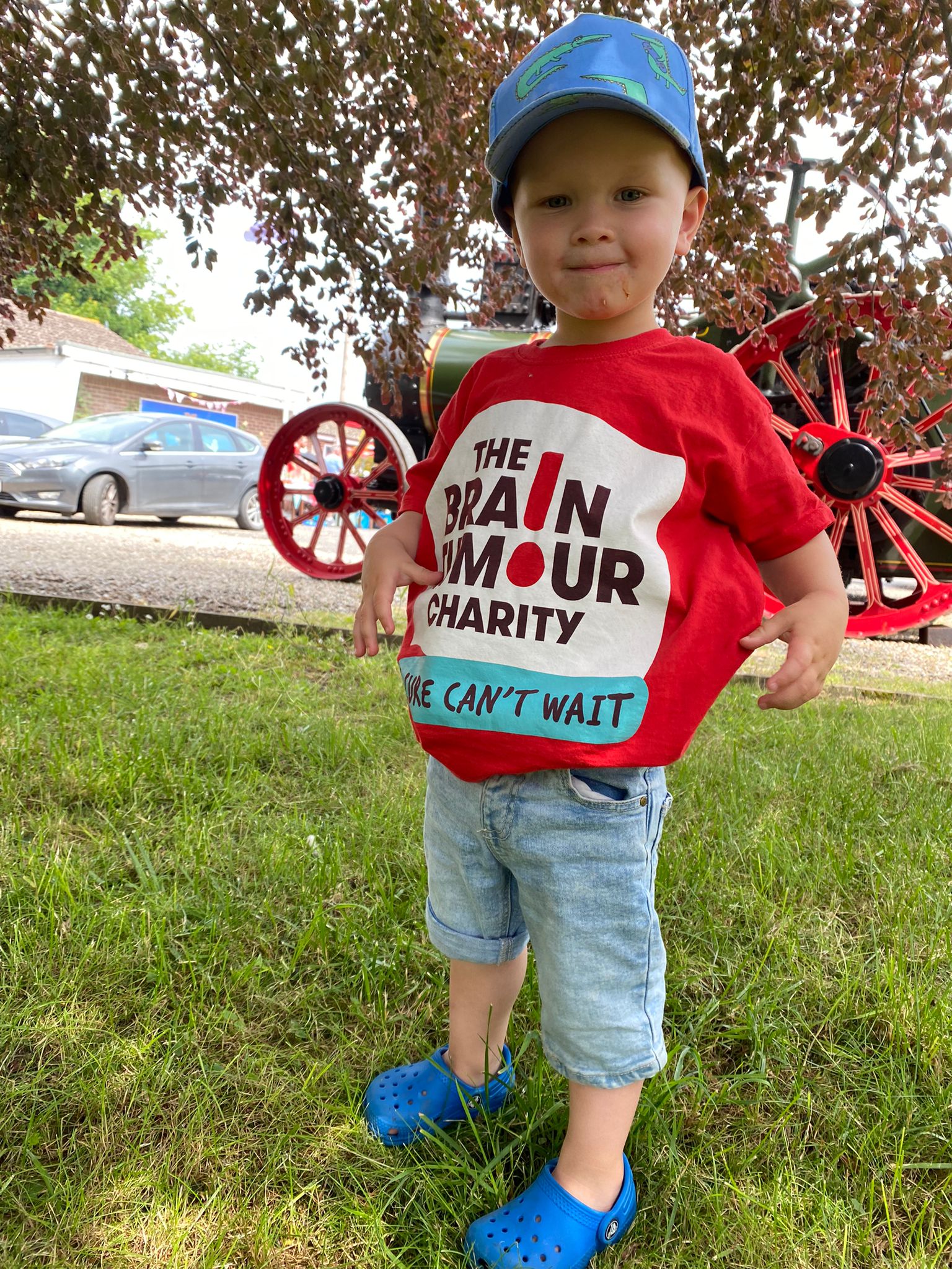 A young boy smiles while wearing The Brain Tumour Charity t-shirt