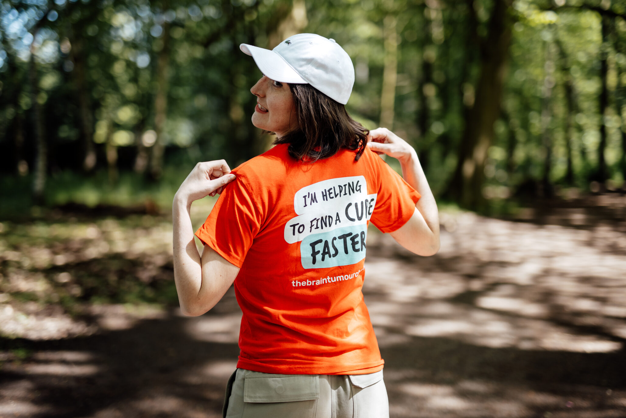 Sophie, known as Brainbabe, shows the back of her The Brain Tumour Charity t-shirt as she stands in a forest