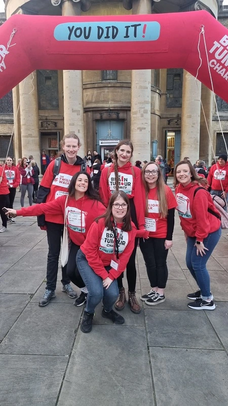 A group of Young Ambassadors smile under a finishing arch for an event by The Brain Tumour Charity