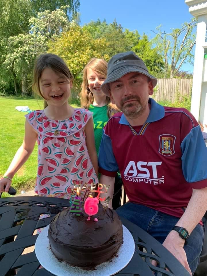 Peter Smallbone in an Aston Villa football shirt with his two children. Peter is sitting in front of a birthday cake with candles. He was just 47 when he died from a glioblastoma.