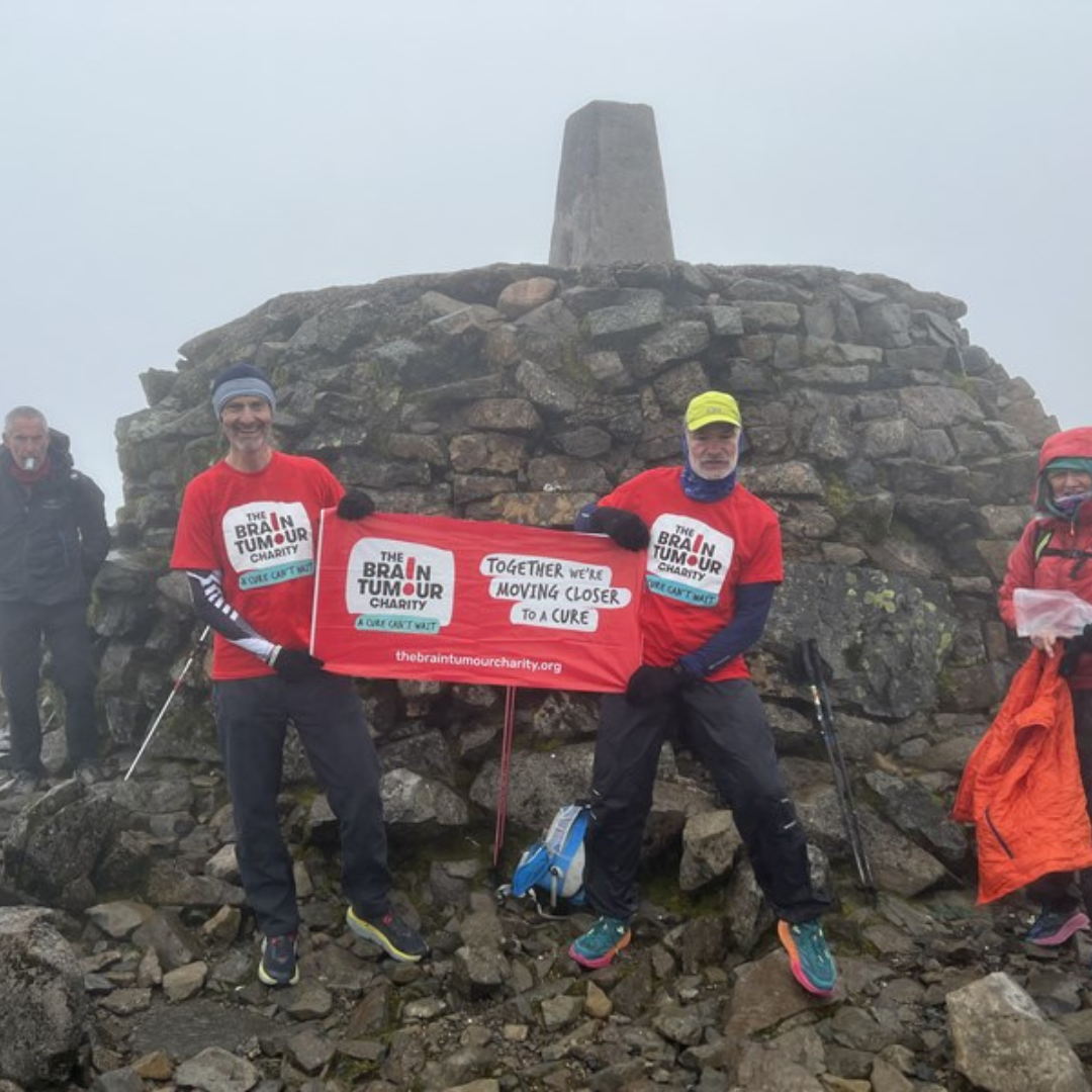 Two men at the top of Ben Nevis after completing the Three Peaks Challenge