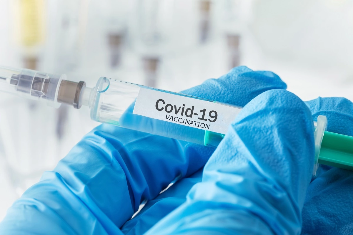 gloved hand holding a COVID-19 vaccination injection - COVID-19 vaccine and brain tumours