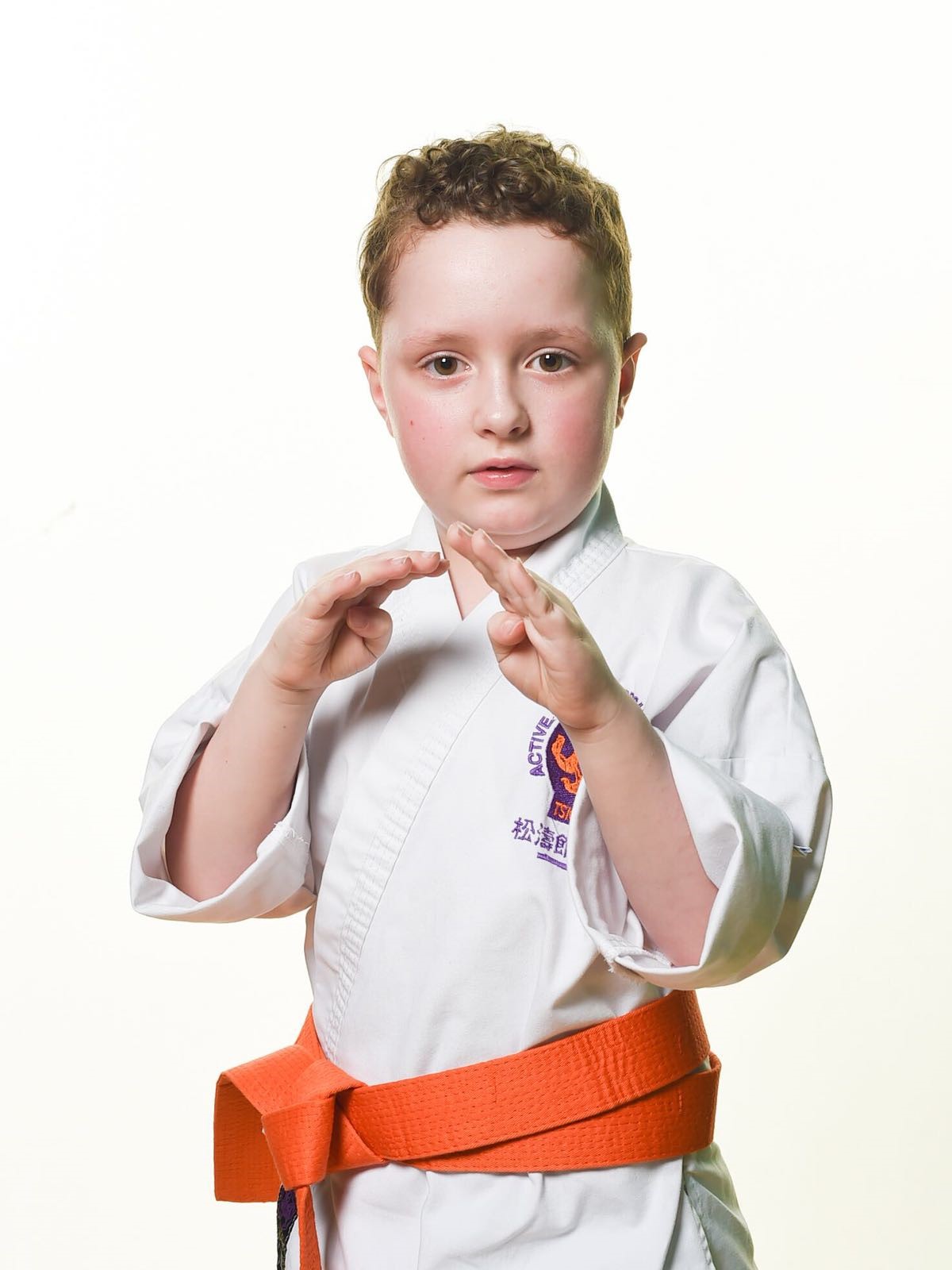 Zac in his white karate kit with orange belt. He doesn't let his optic nerve glioma diagnosis hold him back.