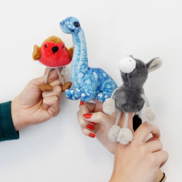 three finger puppets - a robin, a dinosaur, and a donkey - sit on three people's fingers