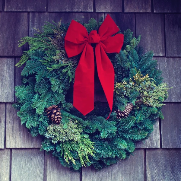 a natural Christmas wreath hanging on a wooden wall