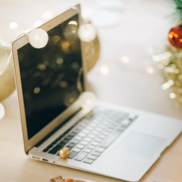 a laptop stands on a desk surrounded by Christmas decorations