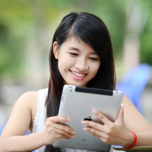 a woman smiles while looking at her iPad