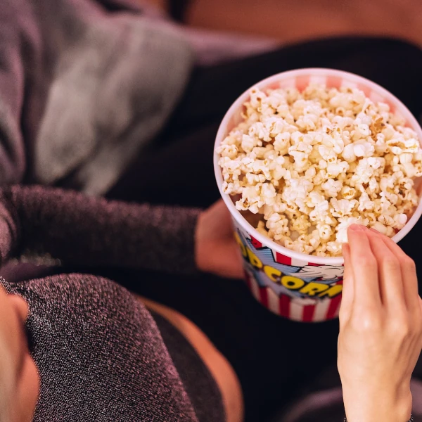 a bucket of popcorn rests on a woman's lap