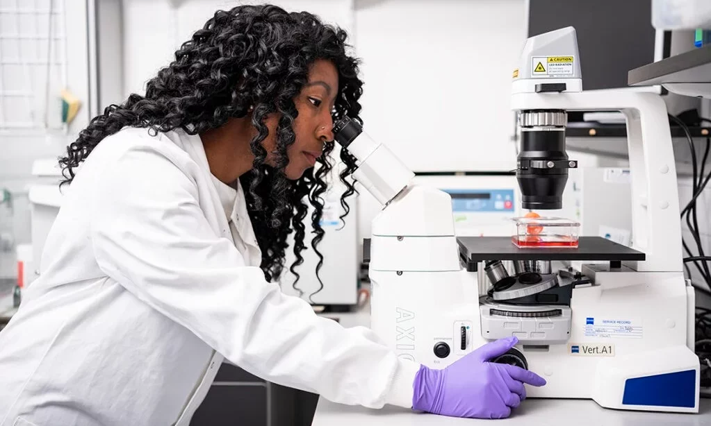 Sigourney, a scientist, looks into a microscope, researching treatments for brain tumours