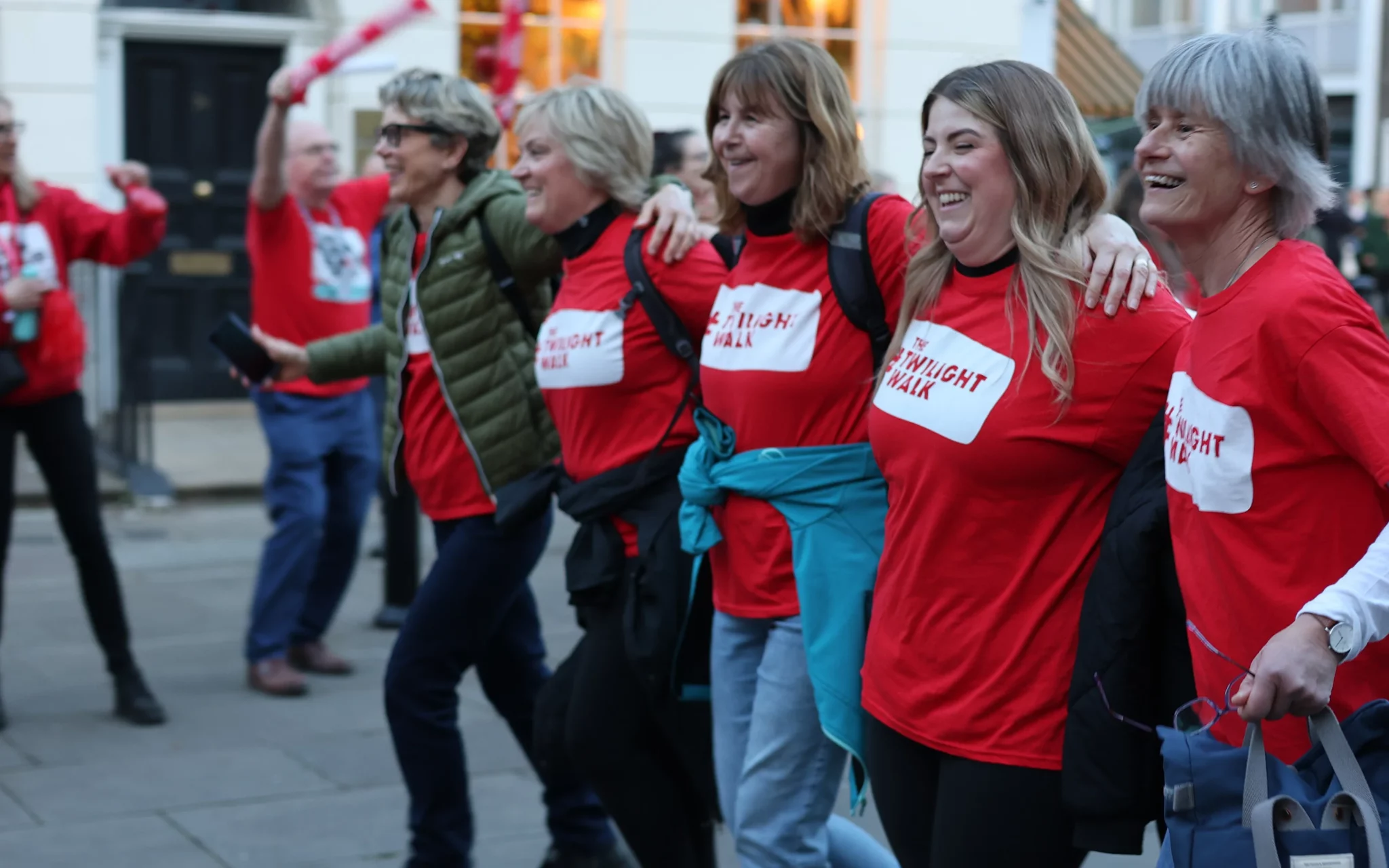 A group of walkers at The Twilight Walk 2025 link arms as they approach the finish line.