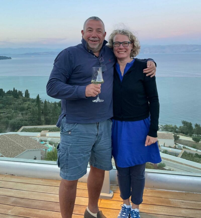 Bill and Helen standing in front of a sunset on holiday