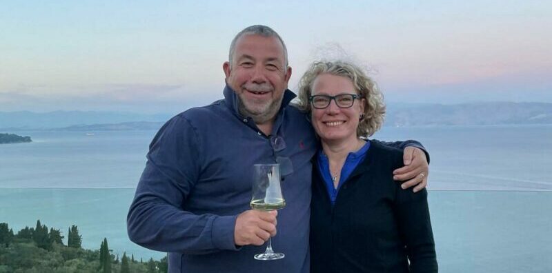 Bill and Helen standing in front of a sunset on holiday