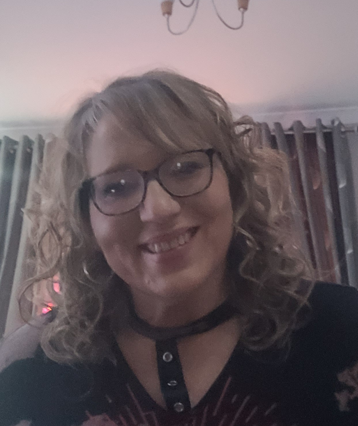 Portrait of Jayne who has mid length wavy hair and spectacles.