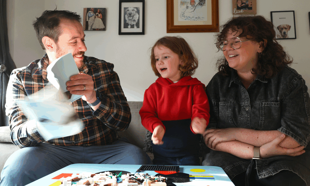Mel laughing with her husband and little boy in their living room
