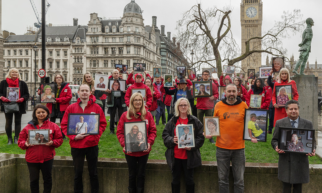 A group of people holding portraits of loved ones at Parliament square in London