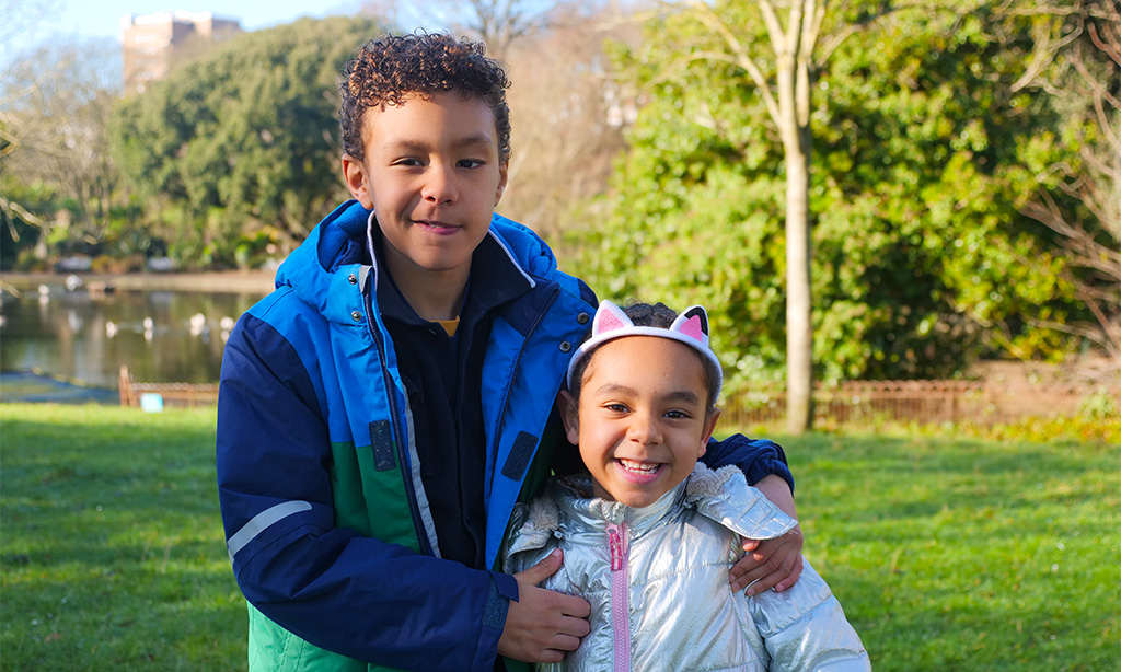 Ravi and his sister Maya outside smiling to camera