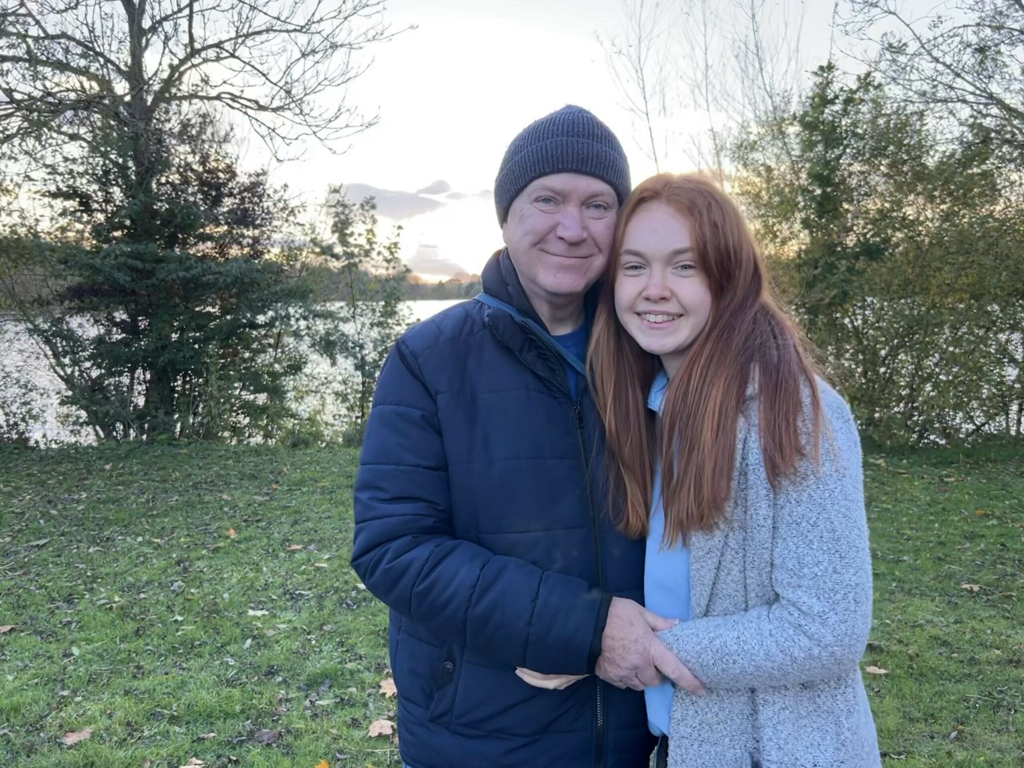 Catherine and her late father Tim stand in front of a lake